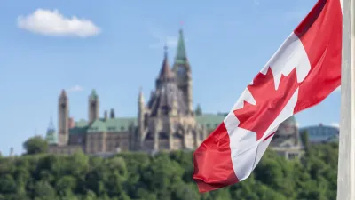 Close-up on Canadian flag with Canada Parliament building blurred in background.